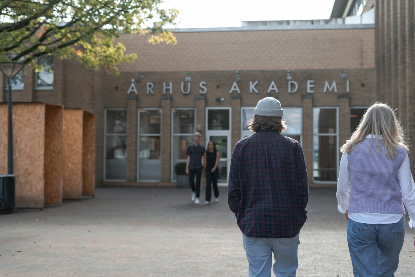 Students walk toward the entrance of a brick campus building.