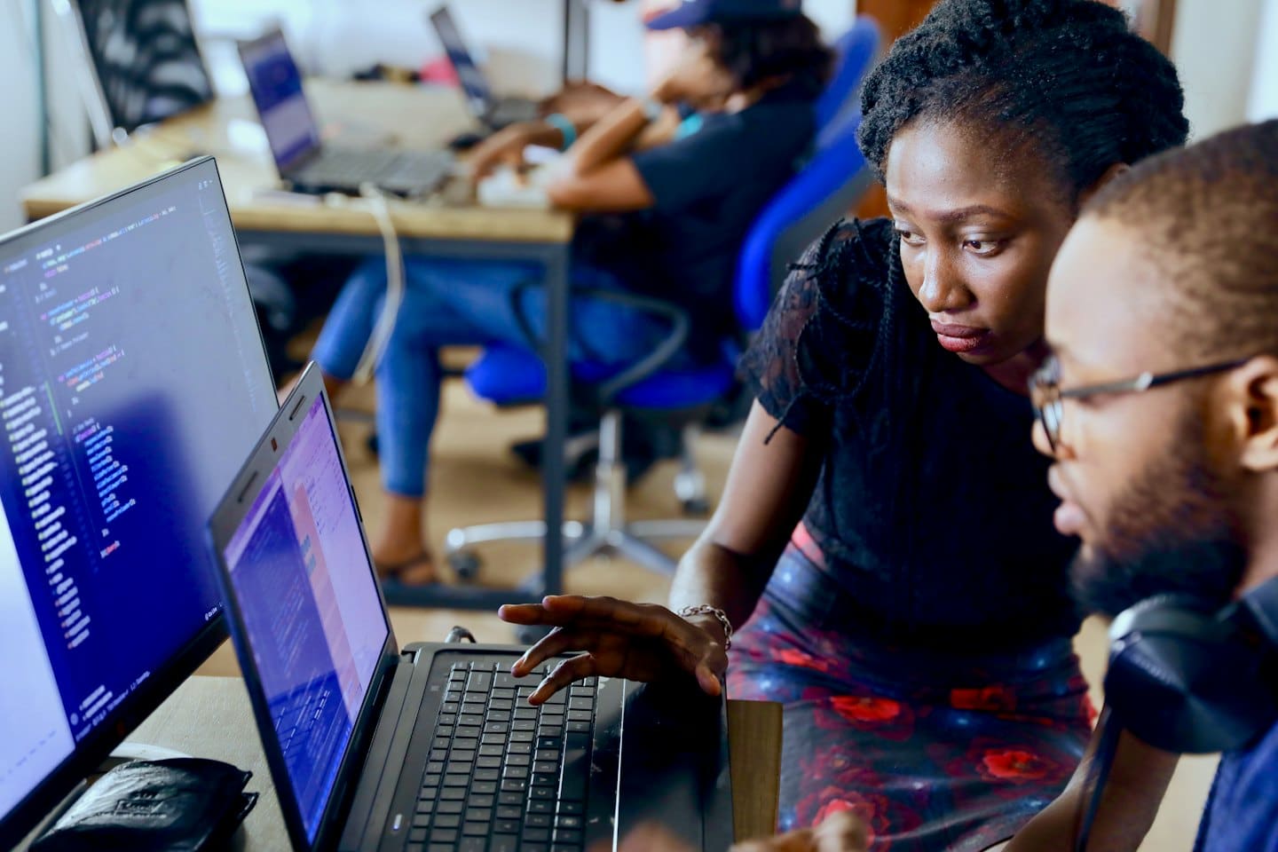 Two people collaborating on programming code on a laptop.