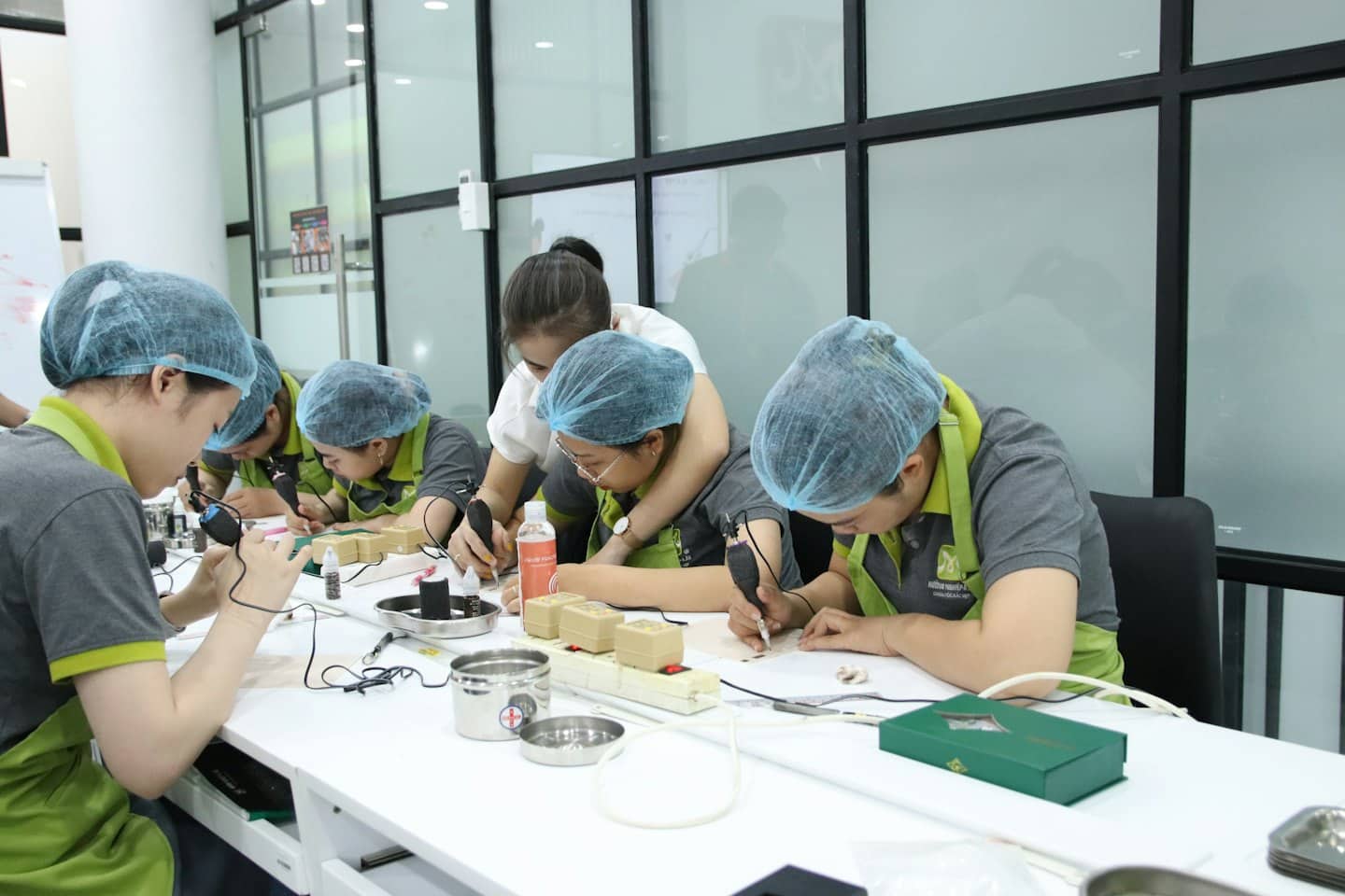 Instructor guides students practicing permanent makeup techniques on training blocks.